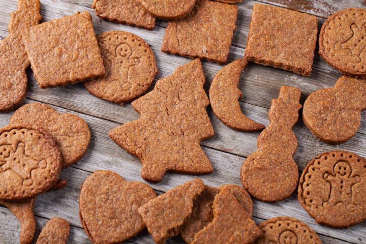 Shaped speculoos cookies laid out on a wooden table.