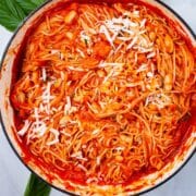 A large pan with spaghetti and a red tomato sauce with beans topped with cheese.