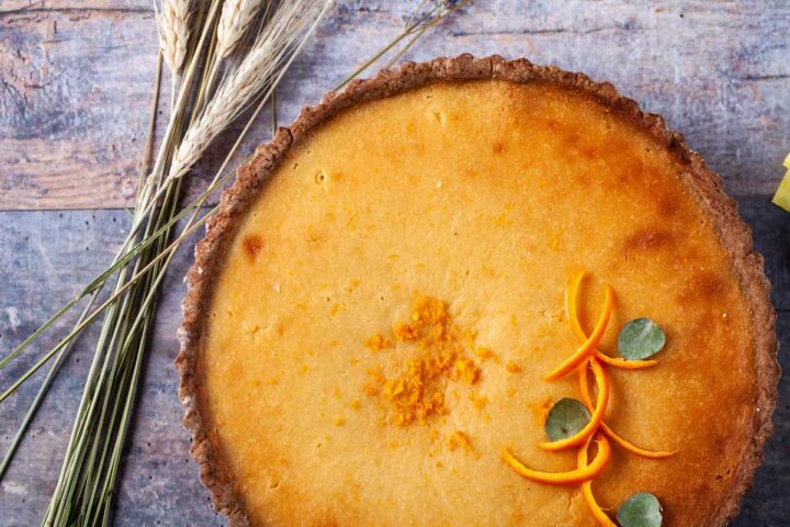 A beautiful golden tart topped with curled orange peels and fall leaves.