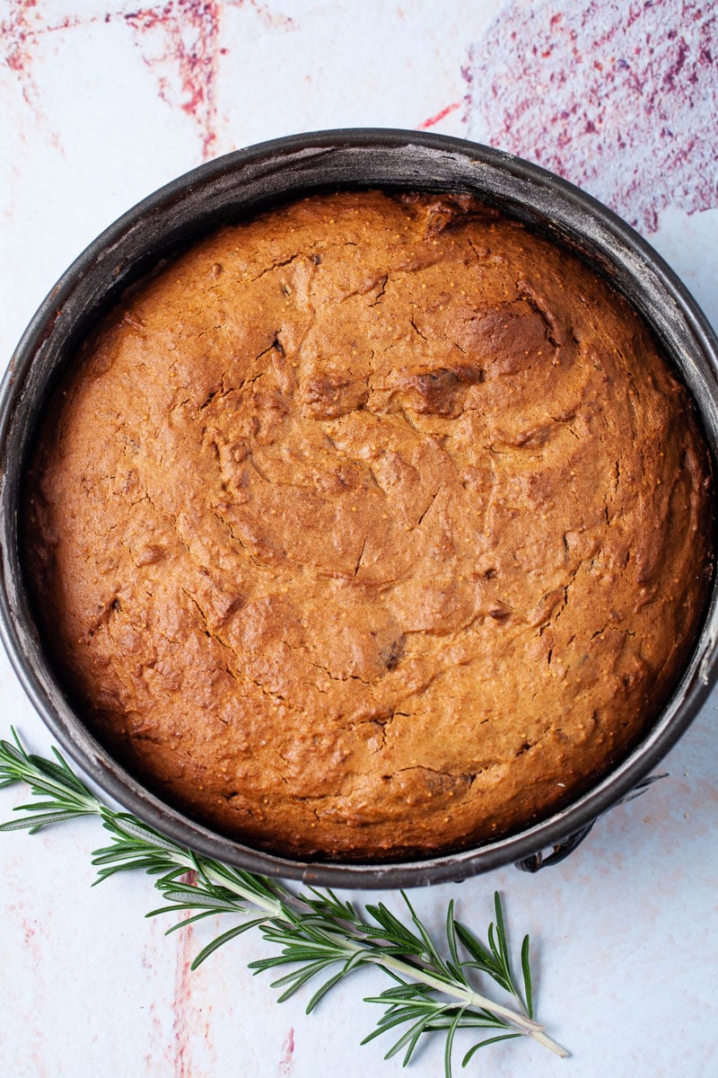 A baked fig and walnut cake resting in a cake pan.