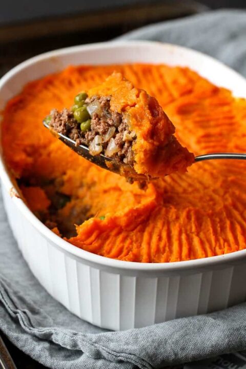 a spoon lifting up a scoop of sweet potato topped bison shepherd's pie.