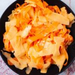 Seasoned raw carrot salad with apples on a serving plate.