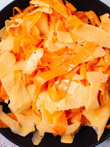 Seasoned raw carrot salad with apples on a serving plate.