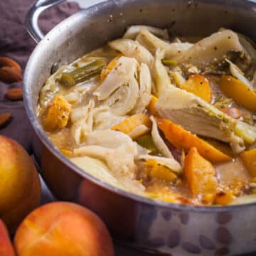 Soft braised fennel pieces and peaches in a creamy liquid in a large pan.