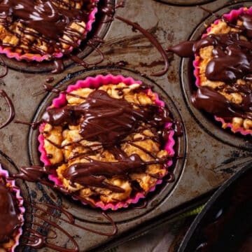 Rice crispy treats in cupcake holders covered with melted chocolate.