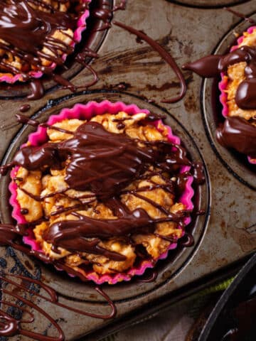 Rice crispy treats in cupcake holders covered with melted chocolate.