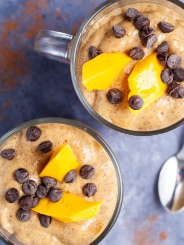 Two creamy chocolate mango smoothies topped with chocolate chips and fresh mango slices.