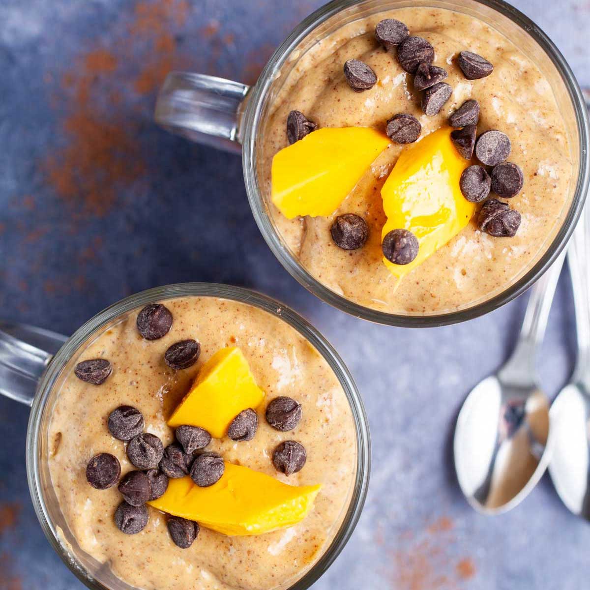Two creamy chocolate mango smoothies topped with chocolate chips and fresh mango slices.