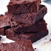 Dark chocolate squared date brownies stacked on top of each other.