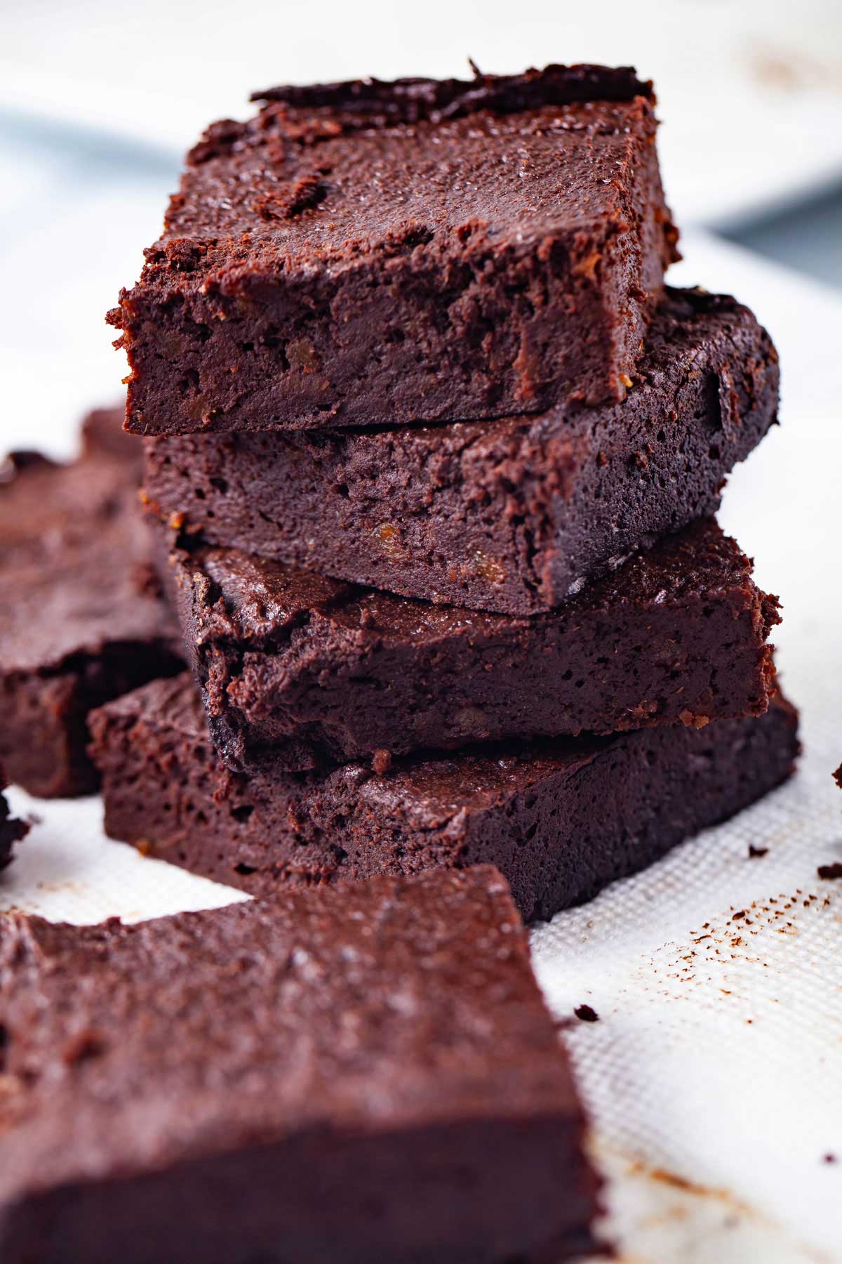 Dark chocolate squared date brownies stacked on top of each other.