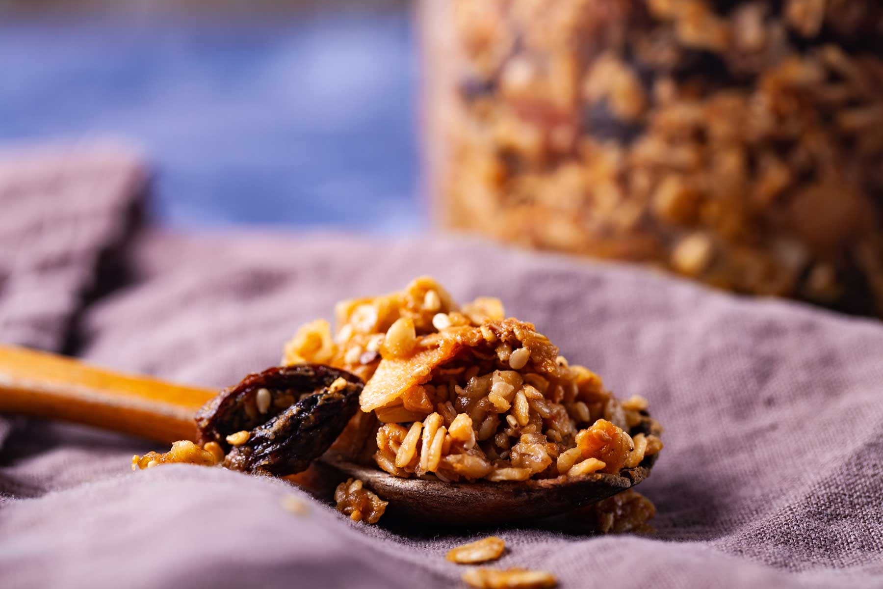 A wooden spoon with baked granola resting on a table.