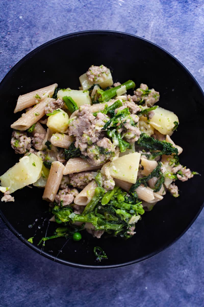 A plate filled with pasta with broccoli rabe and sausages.