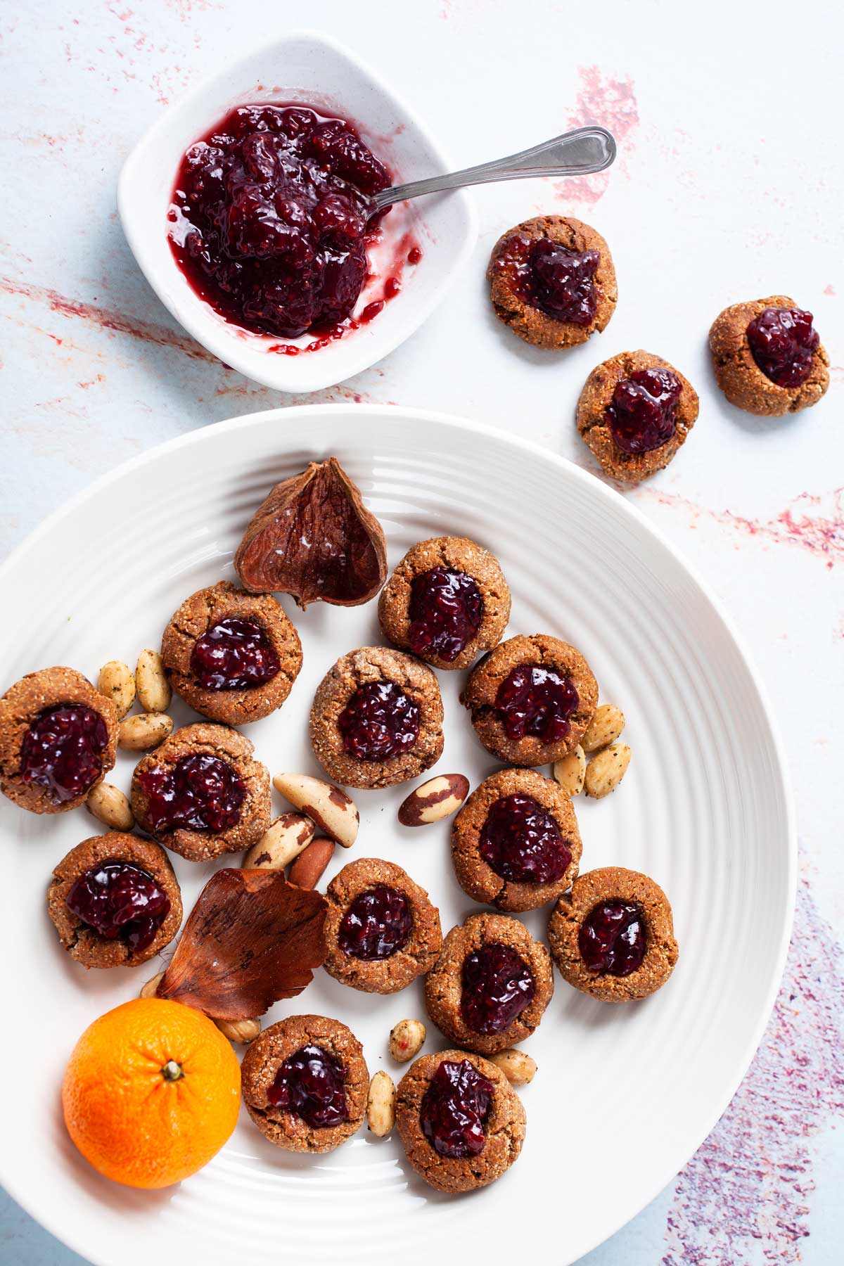 A plate filled with gluten-free almond flour cookies, topped with jam.