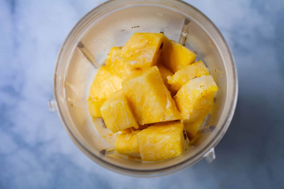 Chopped pineapple in a blender.