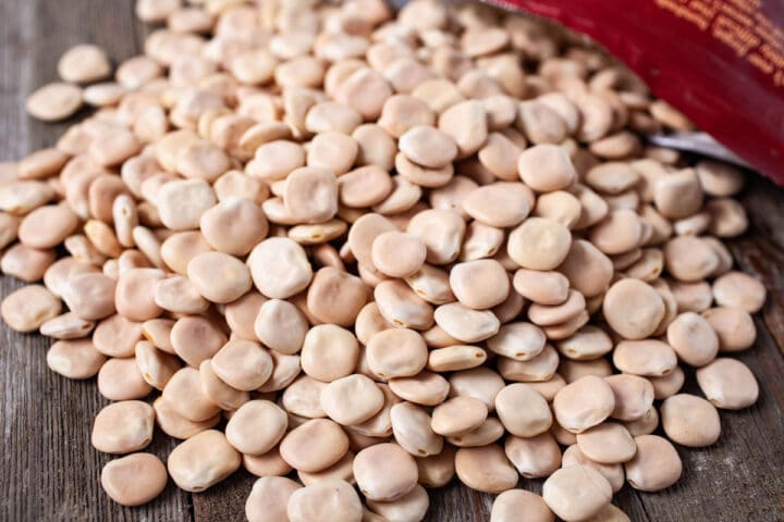 Frijoles de altramuz crudos esparcidos en una tabla de madera.