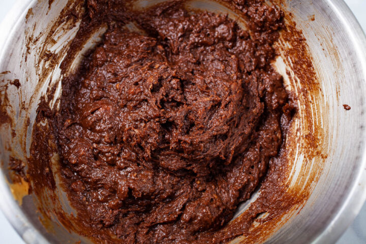 Brown cookie batter in a stainless steel bowl.