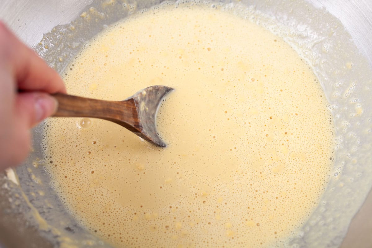 Someone stirring a wooden spoon in a batter.