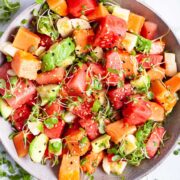 A watermelon fruit salad with papaya and avocado and crunchy seeds served in a bowl.