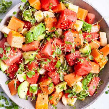 A watermelon fruit salad with papaya and avocado and crunchy seeds served in a bowl.