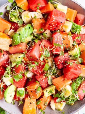 A watermelon fruit salad with papaya and avocado and crunchy seeds served in a bowl.
