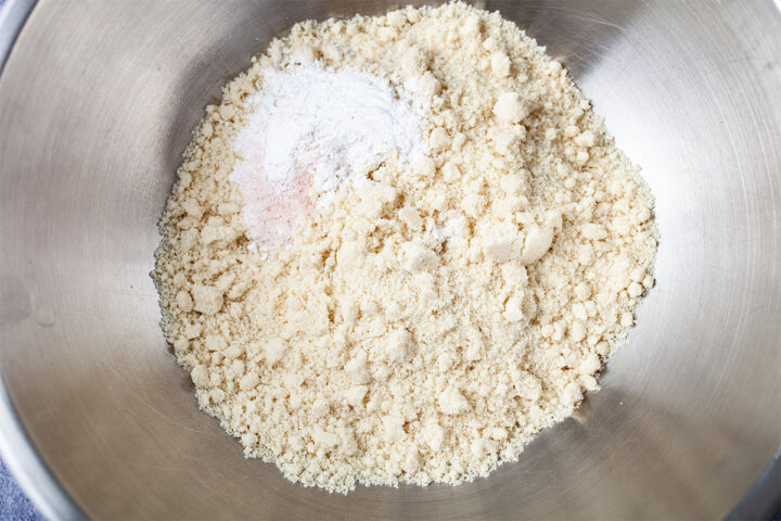 Baking powder and some salt on top of almond flour in a stainless steel bowl.