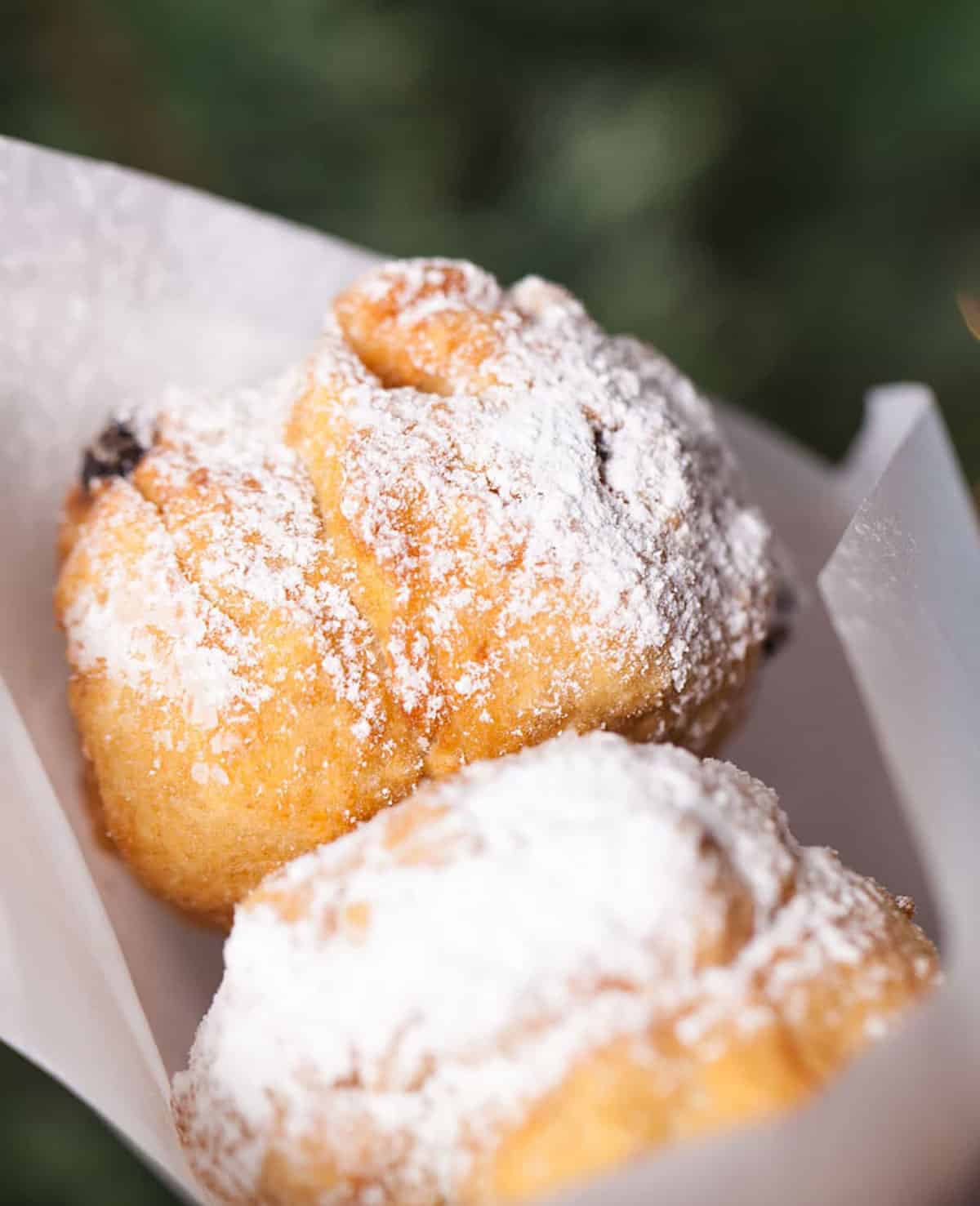 Italian fried doughnuts in a paper bag topped with powdered sugar.