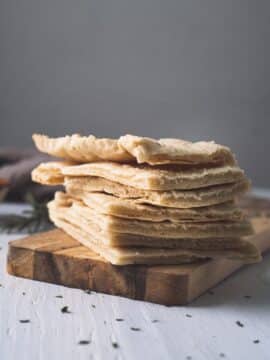 Flat bread stacked on a wooden board.