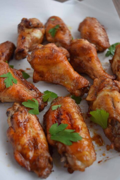 an up close shot of chinese five spice chicken wings garnished with some fresh parsley.